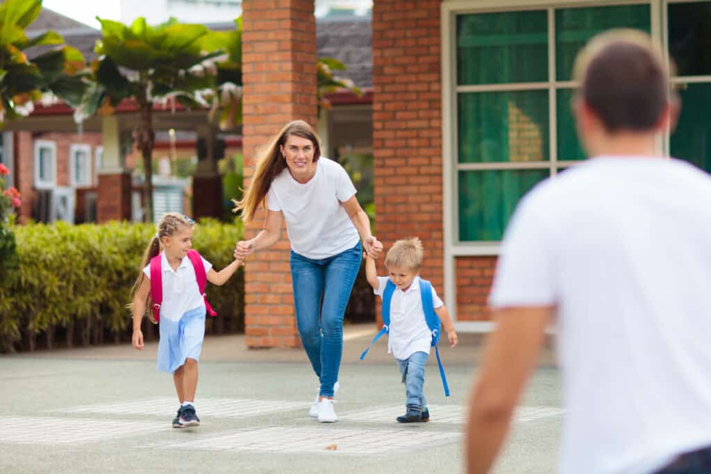 Young mom picking up children after lessons in kindergarten or preschool.